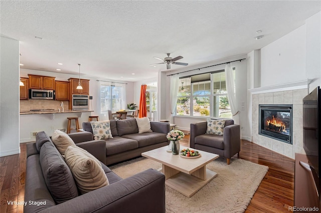 26004 E Elmhurst Pl, Aurora, CO 80016 - living room with dark wood-style floors, a fireplace, recessed lighting, ceiling fan, and a textured ceiling