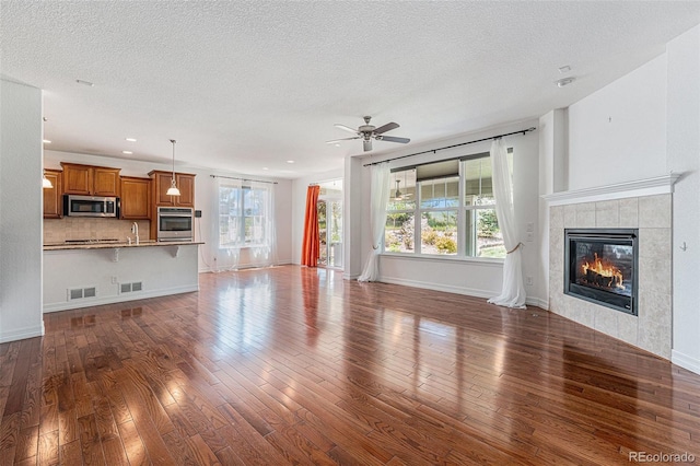 26004 E Elmhurst Pl, Aurora, CO 80016 - unfurnished living room featuring wood finished floors, a ceiling fan, healthy amount of natural light, a textured ceiling, and recessed lighting