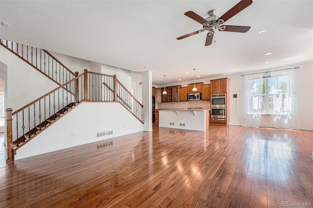 26004 E Elmhurst Pl, Aurora, CO 80016 - unfurnished living room featuring wood finished floors, stairs, a ceiling fan, recessed lighting, and baseboards