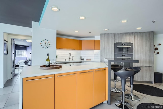 kitchen featuring light countertops, double wall oven, modern cabinets, and tasteful backsplash