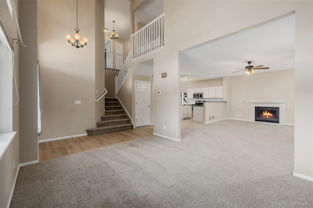 9417 Burgundy Cir, Highlands Ranch, CO 80126 - unfurnished living room featuring light colored carpet, a chandelier, ceiling fan, stairway, and a tiled fireplace
