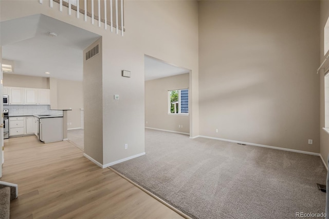 9417 Burgundy Cir, Highlands Ranch, CO 80126 - unfurnished living room with a towering ceiling and light wood-style flooring