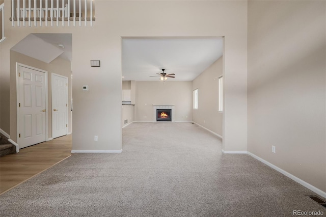 9417 Burgundy Cir, Highlands Ranch, CO 80126 - unfurnished living room featuring carpet flooring, a ceiling fan, a fireplace, and stairs