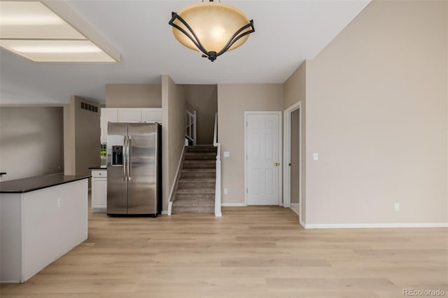 9417 Burgundy Cir, Highlands Ranch, CO 80126 - kitchen featuring stainless steel fridge, dark countertops, white cabinetry, and light wood-style floors