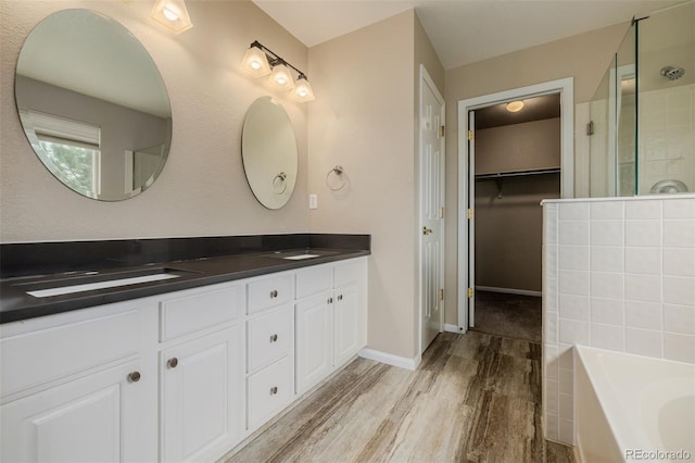 9417 Burgundy Cir, Highlands Ranch, CO 80126 - bathroom with wood finished floors, double vanity, a shower stall, a garden tub, and a spacious closet