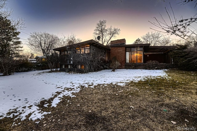 snow covered house featuring a sunroom