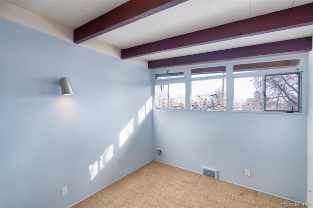 unfurnished room with beamed ceiling and carpet