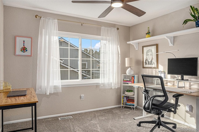 carpeted office with visible vents, baseboards, and a ceiling fan