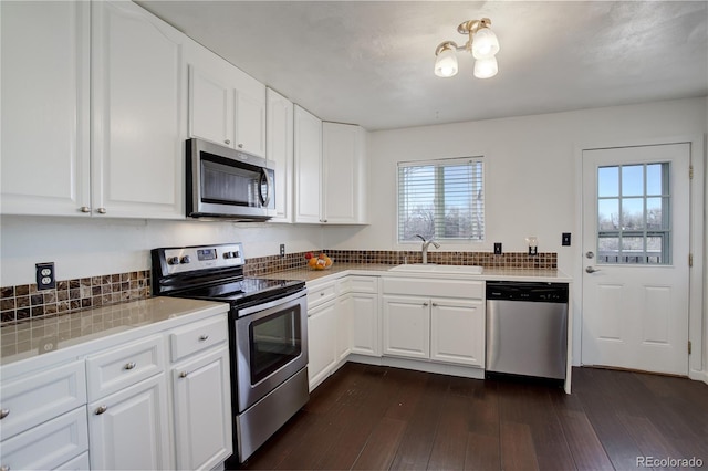 kitchen featuring stainless steel appliances, dark wood-type flooring, sink, white cabinets, and tile counters