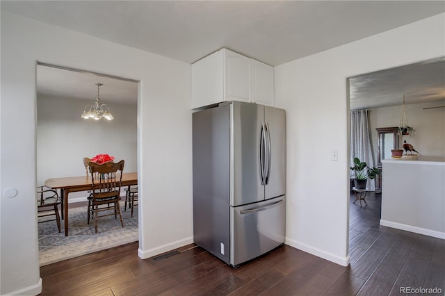 kitchen featuring stainless steel refrigerator, white cabinetry, an inviting chandelier, dark hardwood / wood-style floors, and pendant lighting