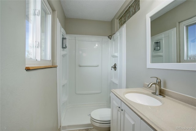 bathroom with a shower, a textured ceiling, vanity, and toilet