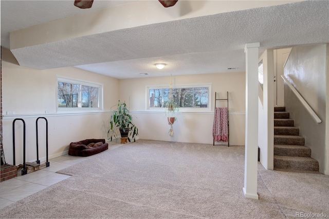 basement featuring a textured ceiling, light carpet, and a wealth of natural light