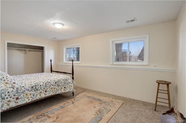 carpeted bedroom featuring a textured ceiling and a closet