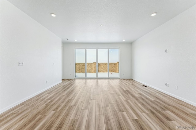 unfurnished room featuring a textured ceiling and light hardwood / wood-style floors