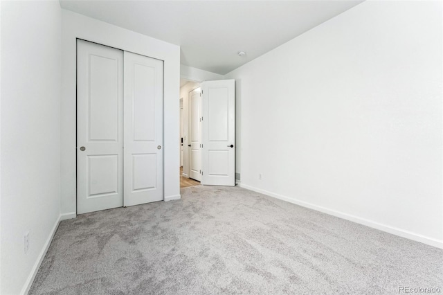 unfurnished bedroom featuring light carpet, lofted ceiling, and a closet