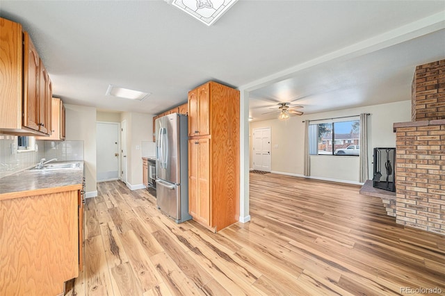 kitchen with sink, stainless steel fridge with ice dispenser, ceiling fan, light hardwood / wood-style floors, and decorative backsplash