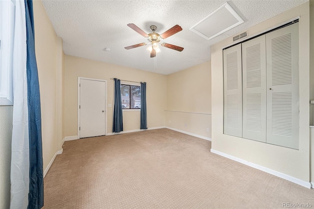 unfurnished bedroom featuring ceiling fan, light colored carpet, a closet, and a textured ceiling