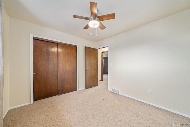 unfurnished bedroom featuring light colored carpet, ceiling fan, and a closet