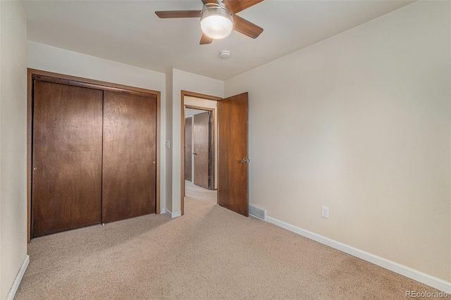 unfurnished bedroom with light colored carpet, a closet, and ceiling fan