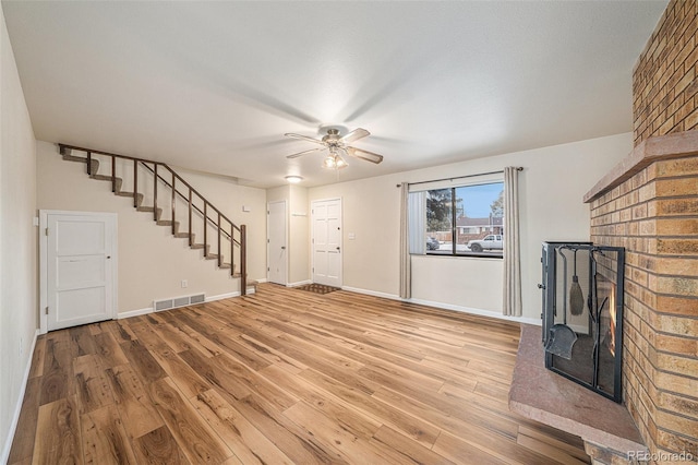 unfurnished living room with ceiling fan, wood-type flooring, and a fireplace