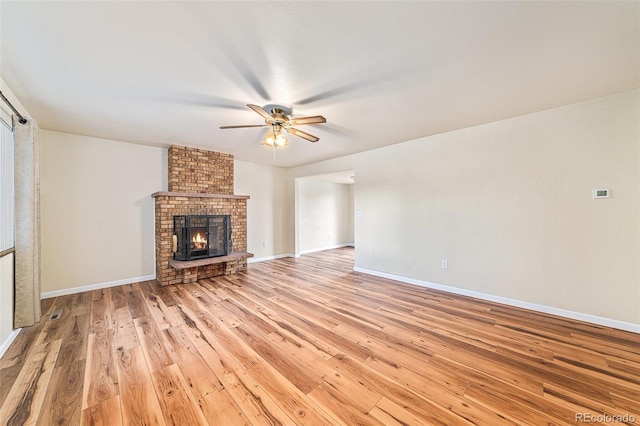 unfurnished living room featuring a brick fireplace, light hardwood / wood-style flooring, and ceiling fan