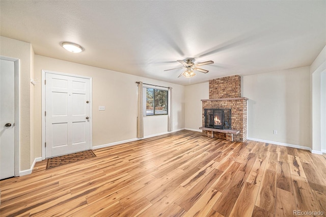 unfurnished living room with ceiling fan, a fireplace, light hardwood / wood-style flooring, and a textured ceiling