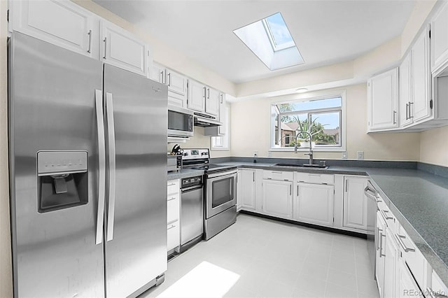 6223 W Flora Pl, Denver, CO 80227 - kitchen featuring appliances with stainless steel finishes, a sink, a skylight, dark countertops, and under cabinet range hood