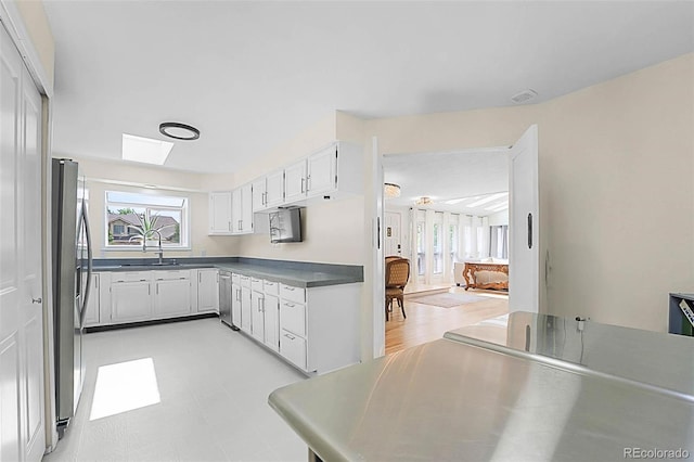 6223 W Flora Pl, Denver, CO 80227 - kitchen featuring appliances with stainless steel finishes, white cabinetry, dark countertops, a sink, and light flooring