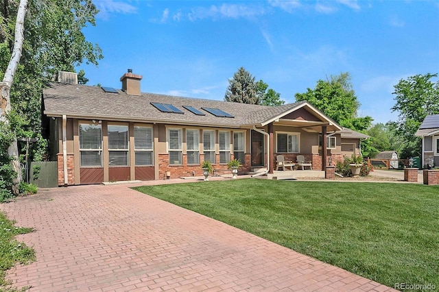 6223 W Flora Pl, Denver, CO 80227 - view of front of property featuring solar panels, a front yard, a chimney, and brick siding