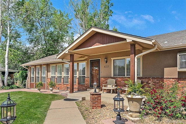 6223 W Flora Pl, Denver, CO 80227 - view of front of house featuring brick siding, a front yard, a shingled roof, and stucco siding