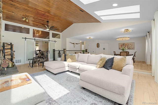 6223 W Flora Pl, Denver, CO 80227 - living room featuring a barn door, light wood-style flooring, wood ceiling, a ceiling fan, and a skylight