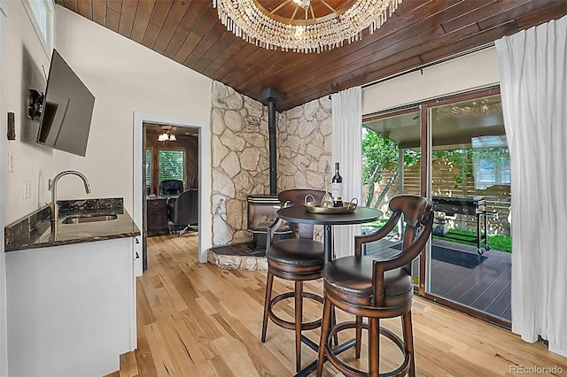 6223 W Flora Pl, Denver, CO 80227 - dining room featuring lofted ceiling, a wood stove, light wood-style floors, a chandelier, and wood ceiling