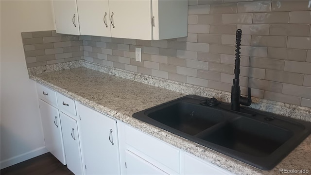 kitchen with backsplash, white cabinetry, and sink