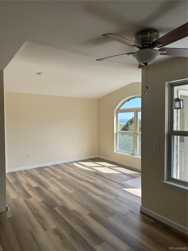 spare room featuring lofted ceiling, hardwood / wood-style flooring, ceiling fan, and a textured ceiling