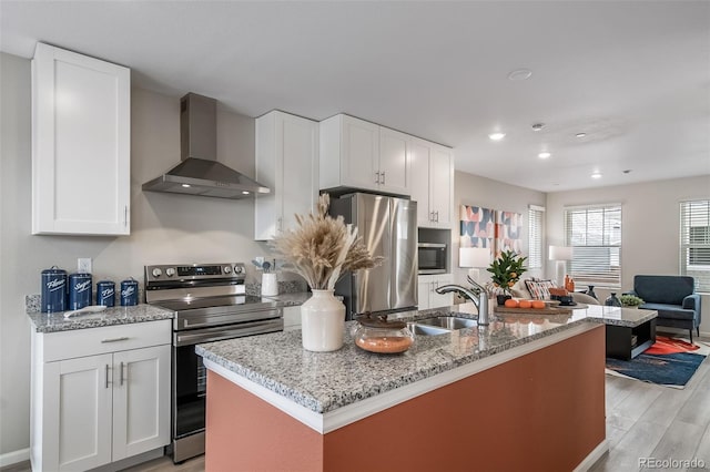 13029 E 103rd Pl, Commerce City, CO 80022 - kitchen featuring wall chimney exhaust hood, appliances with stainless steel finishes, a sink, light wood-style floors, and white cabinets