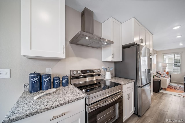 13029 E 103rd Pl, Commerce City, CO 80022 - kitchen featuring appliances with stainless steel finishes, wall chimney range hood, light wood-style floors, white cabinets, and light stone counters