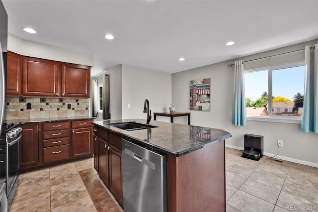 1065 Harbourne St, Colorado Springs, CO 80911 - kitchen featuring appliances with stainless steel finishes, a sink, tasteful backsplash, dark stone countertops, and a center island with sink