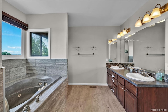 1065 Harbourne St, Colorado Springs, CO 80911 - full bathroom featuring double vanity, a whirlpool tub, baseboards, and wood finished floors