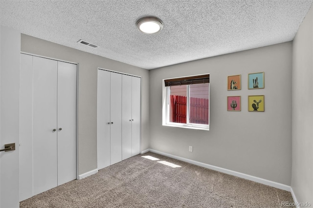 1065 Harbourne St, Colorado Springs, CO 80911 - unfurnished bedroom featuring multiple closets, carpet flooring, a textured ceiling, and baseboards