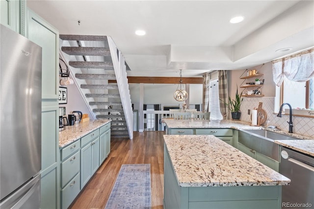 kitchen with sink, light stone countertops, appliances with stainless steel finishes, and a kitchen island