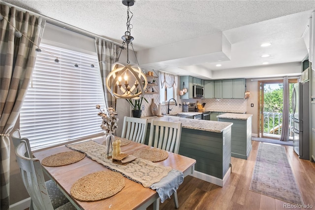 dining area with an inviting chandelier, sink, light hardwood / wood-style flooring, and a textured ceiling