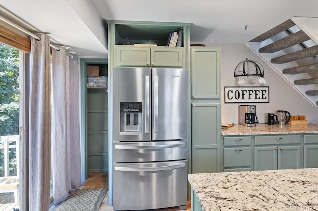 kitchen featuring light stone countertops, green cabinets, and stainless steel fridge