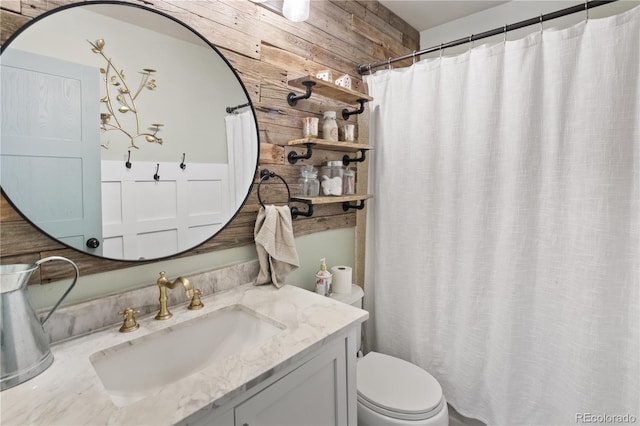 bathroom with toilet, vanity, and wooden walls