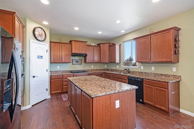 kitchen with fridge, a center island, light stone countertops, dark wood-type flooring, and black dishwasher