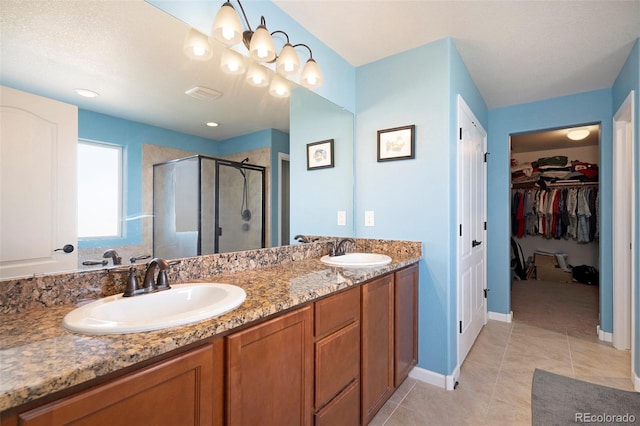 bathroom with vanity, a textured ceiling, tile patterned floors, and a shower with door