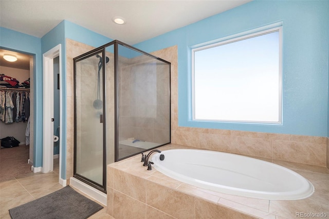 full bath with a spacious closet, tile patterned flooring, a shower stall, and a garden tub