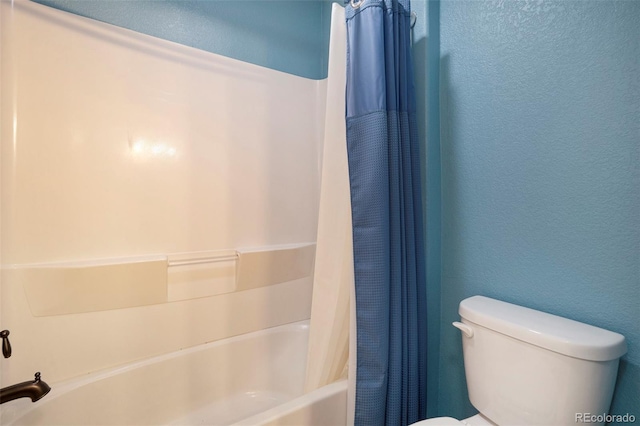 full bath featuring toilet, shower / tub combo, and a textured wall