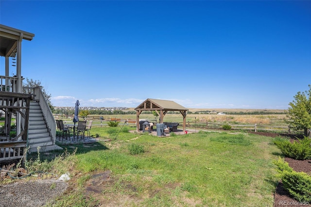 view of yard with a gazebo, stairway, a rural view, and fence