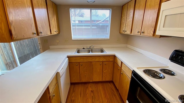 kitchen featuring a sink, light wood-type flooring, white appliances, and light countertops