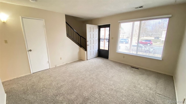 unfurnished room featuring visible vents, light colored carpet, and stairs